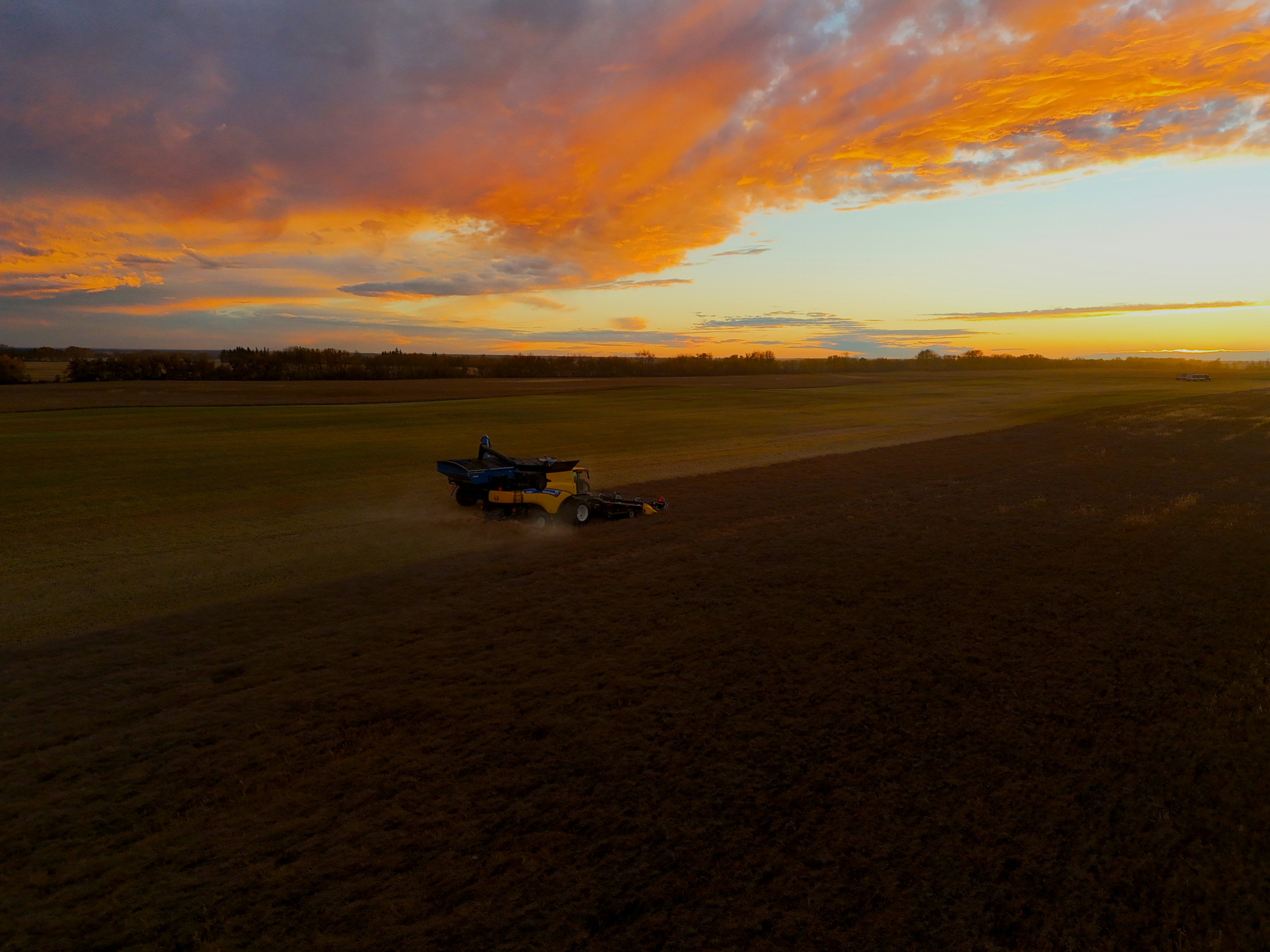 Agricultural field with harvesting machinery at sunset